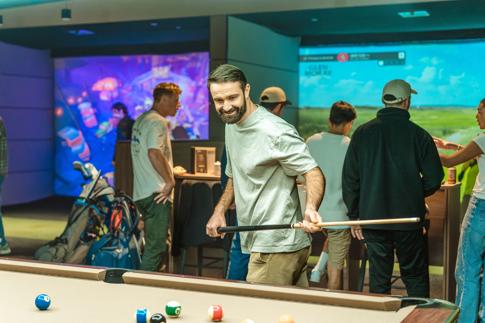 Mate lining up a pool shot with simulators in the background
